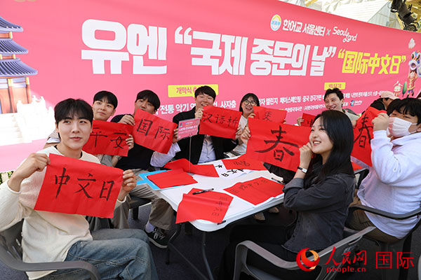 参加文化体验项目的人员手持自己书写的汉字合影留念。人民网记者 莽九晨摄